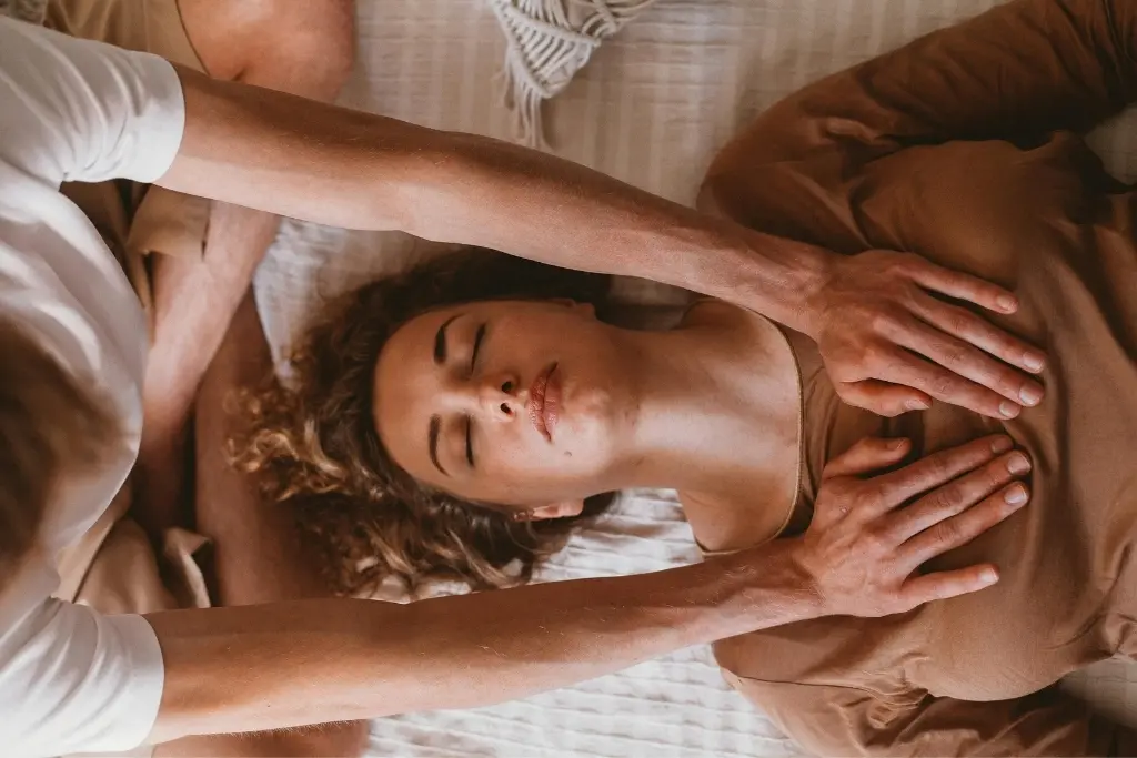 Mujer recibiendo un tacto consciente en el pecho, con los ojos cerrados y expresión serena, reflejo de la filosofía del contacto en Alquimia del Contacto